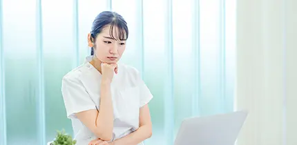パソコンの前で悩む女性